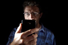 Feche acima do retrato do homem novo que olha intensivamente à tela do telefone celular com os olhos azuis largos abrem isolado n foto de stock Feche acima do retrato do homem novo que olha intensivamente à tela do telefone celular com os olhos azuis largos abrem isolado n foto de stock