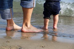 Feet of the men and baby standing in shallow water waiting for the wave stock image Feet of the men and baby standing in shallow water waiting for the wave stock image