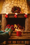 Feet in woollen socks by the Christmas fireplace. Woman relaxes Royalty Free Stock Photography Feet in woollen socks by the Christmas fireplace. Woman relaxes Royalty Free Stock Photography