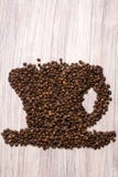 Feij?es de caf? Roasted como um copo em um fundo de madeira imagem de stock Feij?es de caf? Roasted como um copo em um fundo de madeira imagem de stock