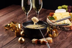 Feinschmeckerisches Schweizer Fondue-Essen an einem Winterabend mit sortierten Käsen auf einem Brett neben einem erhitzten Topf d lizenzfreie stockbilder Feinschmeckerisches Schweizer Fondue-Essen an einem Winterabend mit sortierten Käsen auf einem Brett neben einem erhitzten Topf d lizenzfreie stockbilder