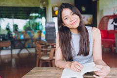 Felice sveglio teenager asiatico del libro di lettura di sorriso bello fotografia stock libera da diritti Felice sveglio teenager asiatico del libro di lettura di sorriso bello fotografia stock libera da diritti
