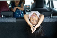 Felicidad de la hija en mirada de la parte posterior de asiento de nuevo al equipaje con la posición de la voltereta foto de archivo Felicidad de la hija en mirada de la parte posterior de asiento de nuevo al equipaje con la posición de la voltereta foto de archivo