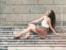 Felicidad y belleza Mujer joven sonriente que se sienta en pasos fotos de archivo Felicidad y belleza Mujer joven sonriente que se sienta en pasos fotos de archivo