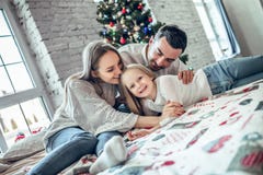 Feliz Natal e ano novo feliz! A família feliz está encontrando-se na cama perto da árvore de Natal bonita fotografia de stock Feliz Natal e ano novo feliz! A família feliz está encontrando-se na cama perto da árvore de Natal bonita fotografia de stock