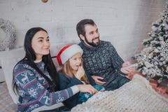 Feliz Natal e ano novo feliz Família nova que comemora o feriado em casa O pai está guardando o telecontrole do imagem de stock Feliz Natal e ano novo feliz Família nova que comemora o feriado em casa O pai está guardando o telecontrole do imagem de stock
