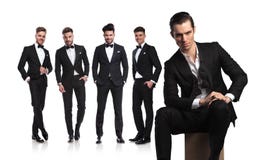 Fem unga män i tuxedoes med ledaren som framme sitter royaltyfri bild Fem unga män i tuxedoes med ledaren som framme sitter royaltyfri bild