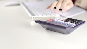 Female accountant using calculator on white desk in office