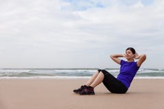Female athlete executing situps at the beach stock image Female athlete executing situps at the beach stock image
