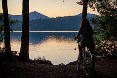 Female on a bicycle enjoying the view of the sea with mountains in the background stock photo Female on a bicycle enjoying the view of the sea with mountains in the background stock photo