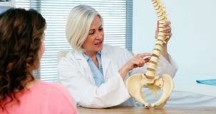 Female doctor explaining spine model to female patient