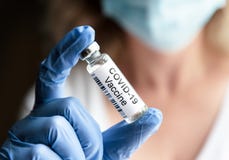 Female doctor holds bottle with COVID-19 coronavirus vaccine in laboratory