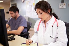 Female Doctor With Male Nurse Working At Nurses Station stock photo Female Doctor With Male Nurse Working At Nurses Station stock photo