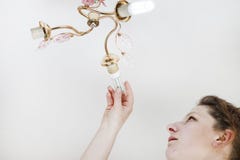 Female hand inserts a light bulb into the threaded socket. she is shining. Installation of household LED lamps of corn type, in royalty free stock images Female hand inserts a light bulb into the threaded socket. she is shining. Installation of household LED lamps of corn type, in royalty free stock images