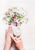 Female hands apply cream on skin on white background with plants and flowers , top view. royalty free stock image Female hands apply cream on skin on white background with plants and flowers , top view. royalty free stock image