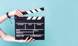 Female Hands Holding A Clapper Board Isolated On Blue Stock Photography