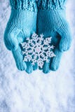 Female hands in light teal knitted mittens with sparkling wonderful snowflake on a white snow background. Winter Christmas concept Stock Photo Female hands in light teal knitted mittens with sparkling wonderful snowflake on a white snow background. Winter Christmas concept Stock Photo