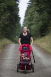 Female Jogger pushing her baby in a baby stroller while on a run stock photography Female Jogger pushing her baby in a baby stroller while on a run stock photography