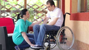 Female nurse consoling sad man sitting in wheelchair stock footage Female nurse consoling sad man sitting in wheelchair stock footage