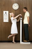 Female nurse weighing man on scale. Royalty Free Stock Photography Female nurse weighing man on scale. Royalty Free Stock Photography