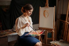 Female painter holds color palette and brush stock photo Female painter holds color palette and brush stock photo