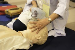 A female physician holding face mask on a mannequin during CPR t stock photos A female physician holding face mask on a mannequin during CPR t stock photos