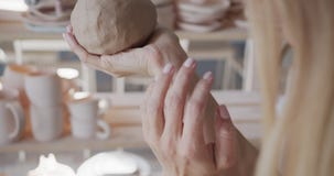 Female potter shaping piece of pottery clay with hands close-up