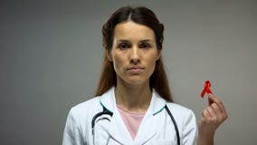 Female therapist showing red ribbon before camera, safe sex, AIDS prevention royalty free stock photo Female therapist showing red ribbon before camera, safe sex, AIDS prevention royalty free stock photo