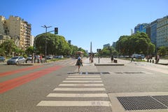 Female Walking on the Crossroad of Avenida 9 de Julio with the Obelisk of Buenos Aires in the Distance, Buenos Aires, Argentina royalty free stock photos Female Walking on the Crossroad of Avenida 9 de Julio with the Obelisk of Buenos Aires in the Distance, Buenos Aires, Argentina royalty free stock photos
