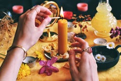Female wiccan witch wearing vintage jewelry lighting a yellow candle on her Litha midsummer Sabbat Solstice celebration altar