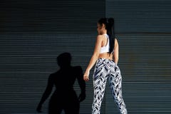 Femelle d'ajustement dans les vêtements de sport se reposant après avoir formé sur le fond noir dehors images libres de droits Femelle d'ajustement dans les vêtements de sport se reposant après avoir formé sur le fond noir dehors images libres de droits