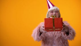 Femelle supérieure gaie dans l'habillement drôle donnant le cadeau d'anniversaire, célébration banque de vidéos Femelle supérieure gaie dans l'habillement drôle donnant le cadeau d'anniversaire, célébration banque de vidéos