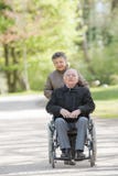 Femme agée poussant l'homme dans le fauteuil roulant photos libres de droits Femme agée poussant l'homme dans le fauteuil roulant photos libres de droits