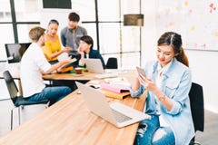Femme asiatique employant l'email futé de contrôle du téléphone APP ou message textuel, équipe diverse multi-ethnique discutant à photos libres de droits Femme asiatique employant l'email futé de contrôle du téléphone APP ou message textuel, équipe diverse multi-ethnique discutant à photos libres de droits