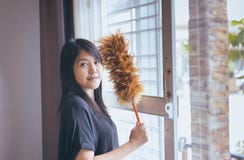 Femme asiatique employant une brosse de la poussière, mains de bonne, époussetant Image stock Femme asiatique employant une brosse de la poussière, mains de bonne, époussetant Image stock