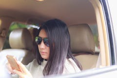 Femme asiatique jouant le smartphone dans la voiture noire photographie stock Femme asiatique jouant le smartphone dans la voiture noire photographie stock