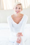 Femme assez blonde souriant à l'appareil-photo tout en se reposant sur le lit Photo stock Femme assez blonde souriant à l'appareil-photo tout en se reposant sur le lit Photo stock