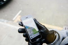 Femme attendant la voiture d'uber sur la rue tenant le smartphone image stock Femme attendant la voiture d'uber sur la rue tenant le smartphone image stock