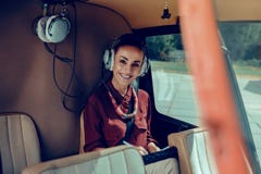 Femme attirante joyeuse étant occupée tout en se reposant sur le siège arrière image stock Femme attirante joyeuse étant occupée tout en se reposant sur le siège arrière image stock