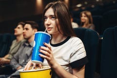 Femme avec la boisson et le maïs éclaté se reposant dans le cinéma images stock Femme avec la boisson et le maïs éclaté se reposant dans le cinéma images stock