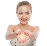 Femme avec le masque facial de farine d'avoine montrant la farine d'avoine photos libres de droits Femme avec le masque facial de farine d'avoine montrant la farine d'avoine photos libres de droits