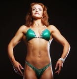 Femme blonde de bodybuilder dans le bikin sur le fond noir Images libres de droits Femme blonde de bodybuilder dans le bikin sur le fond noir Images libres de droits