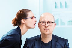 Femme chuchotant dans l'oreille de l'homme au bureau photo stock Femme chuchotant dans l'oreille de l'homme au bureau photo stock