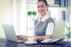 Femme d'affaires heureuse travaillant sur l'ordinateur portable et regardant l'appareil-photo Photo libre de droits Femme d'affaires heureuse travaillant sur l'ordinateur portable et regardant l'appareil-photo Photo libre de droits