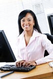 Femme d'affaires noire heureuse au bureau photo libre de droits Femme d'affaires noire heureuse au bureau photo libre de droits