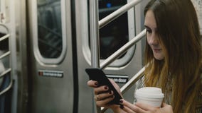 Femme d'affaires sûre attirante heureuse dans le métro utilisant l'appli en ligne de bureau mobile sur le smartphone et le sourir clips vidéos Femme d'affaires sûre attirante heureuse dans le métro utilisant l'appli en ligne de bureau mobile sur le smartphone et le sourir clips vidéos