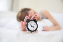 Femme dans le lit commutant outre du réveil photographie stock libre de droits Femme dans le lit commutant outre du réveil photographie stock libre de droits