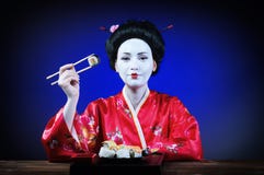 Femme dans le maquillage de geisha mangeant des sushi Photos libres de droits