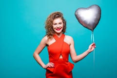 Femme de beauté dans l'équipement rouge de fantaisie posant sur l'appareil-photo avec le ballon de forme de coeur, au-dessus du m photo libre de droits Femme de beauté dans l'équipement rouge de fantaisie posant sur l'appareil-photo avec le ballon de forme de coeur, au-dessus du m photo libre de droits
