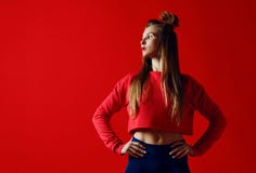 Femme de forme physique dans les vêtements de sport se tenant avec des mains sur des hanches d'isolement au-dessus du fond rouge photos libres de droits Femme de forme physique dans les vêtements de sport se tenant avec des mains sur des hanches d'isolement au-dessus du fond rouge photos libres de droits